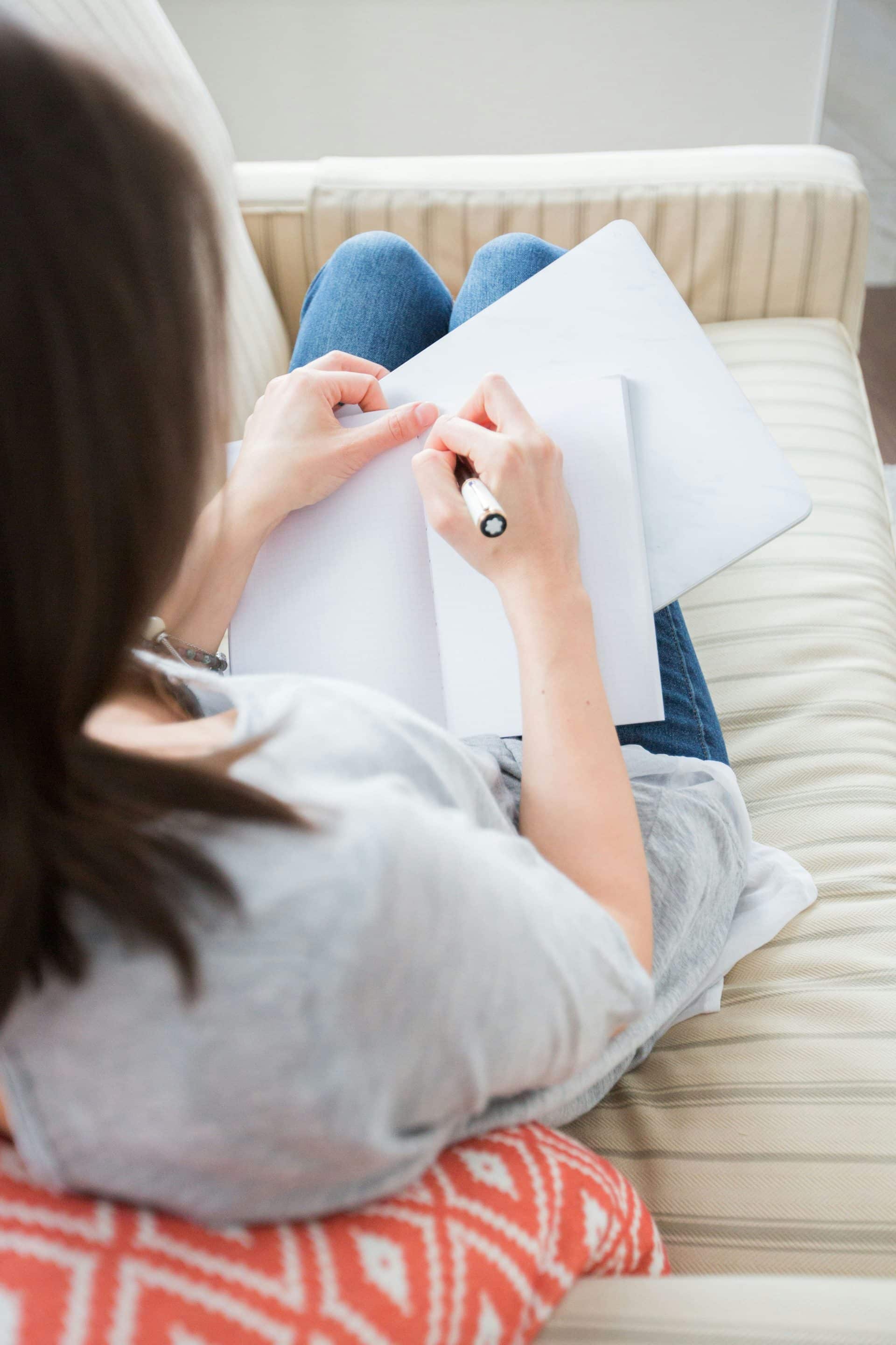 Woman sitting and writing in notebook.