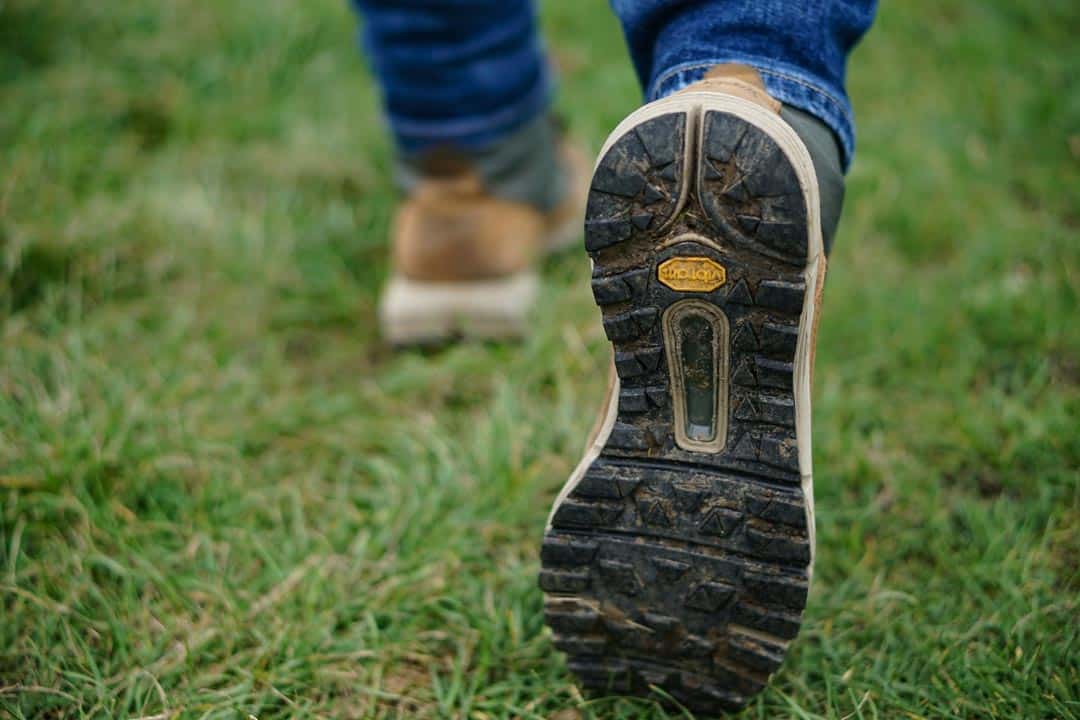 Person walking on grass with hiking boots.